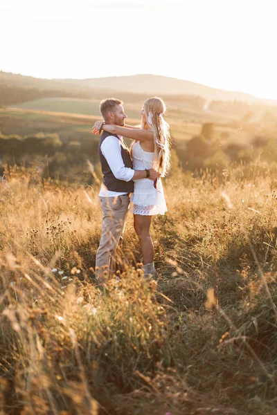Boda rústica y concepto de historia de amor. Boho ypsy mujer y hombre posando en el campo de verano, abrazándose y mirando el uno al otro —  Fotos de Stock
