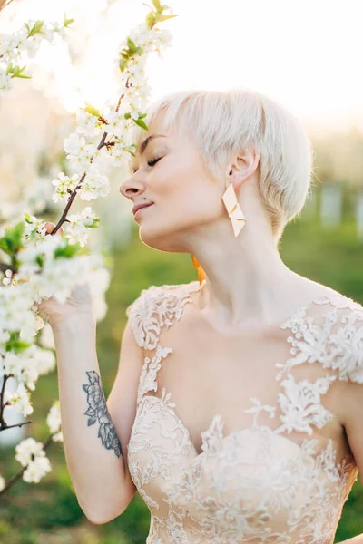 Beauté, personnes, été, printemps et concept de mariage portrait de vue latérale de belle jeune femme touchant branche de fleur d'arbre sur fond de jardin à fleurs vertes — Photo