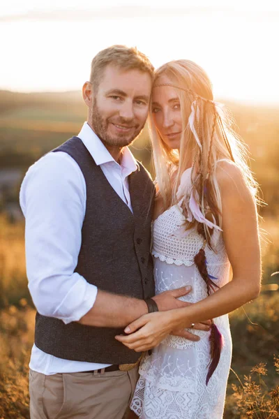 Mariage rustique et concept d'histoire d'amour. Boho femme et homme posant dans le champ d'été, étreignant et regardant la caméra — Photo