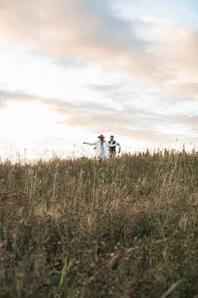 Joyeux famille marchant dans le champ au coucher du soleil et s'amusant. Famille caucasienne joyeuse marchant ensemble dans le champ de campagne — Photo