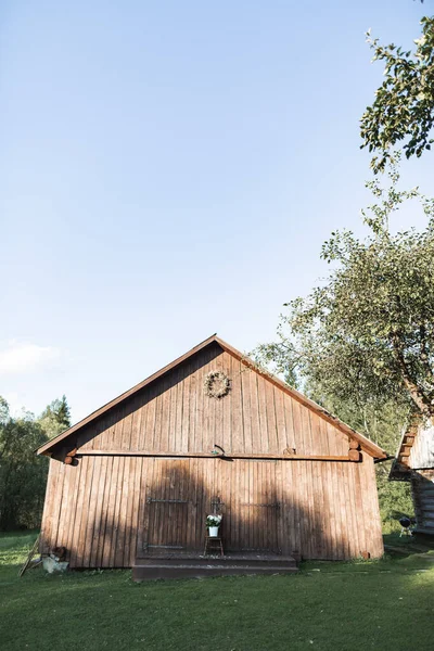 Stylish wooden barn in countryside, on green grass. Summer sunset. Wooden barn in rural area, summer sunset view — Stock Photo, Image