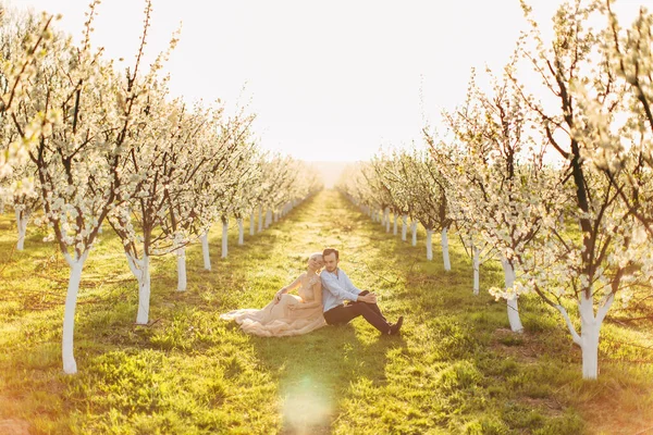 Couple sur une herbe verte au printemps florissant jardin. Deux amoureux assis sur l'herbe, se penchant l'un l'autre dans la matinée ensoleillée dans le beau jardin de printemps. Concepts de printemps, d'amour, de convivialité — Photo