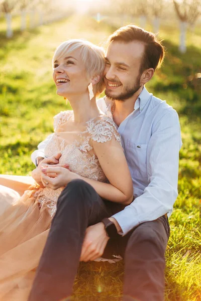 Felice coppia sorridente sul pic-nic nel bellissimo giardino fiorito, mangiare gustosi frutti freschi, godersi la natura primaverile — Foto Stock