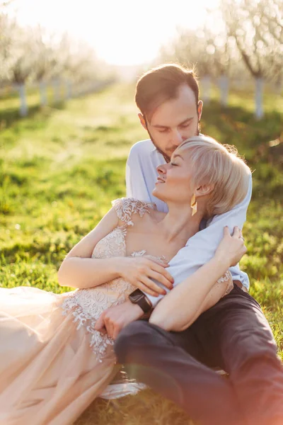 Couple romantique amoureux câliner en plein air, profiter de la date et marcher dans le jardin fleuri de printemps. Femme couchée dans les mains de son homme, tandis que bel homme baisant forehed de son amant — Photo