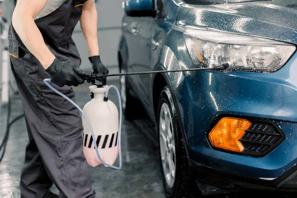 Tvättbil, detaljerat koncept. Närbild bild av manliga biltvätt arbetare bär grå overaller gör bil lätt tvätta med högtrycksvatten jet — Stockfoto