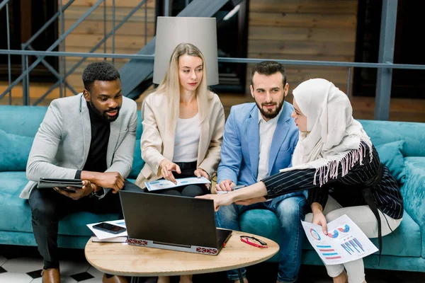 Nahaufnahme von vier smarten jungen multiethnischen Geschäftspartnern, zwei Männern und zwei Frauen, die miteinander Brainstorming betreiben, Ideen und Geschäftsprojekte im schicken Büroraum diskutieren — Stockfoto