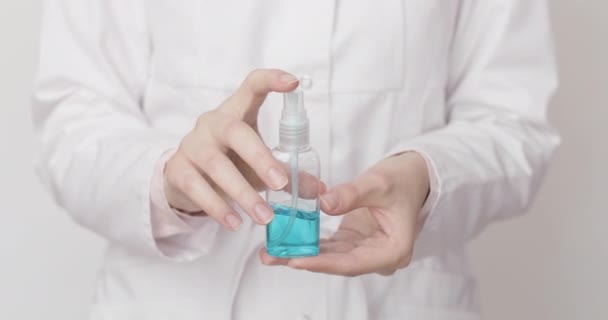 Kvinnliga läkare händer med hjälp av alkohol handdesinfektionsmedel, blå antiseptisk gel, för att förhindra spridning av virus, bakterier och coronavirus vid vit bakgrund. Begreppet personlig hygieniskt desinfektionsmedel — Stockvideo