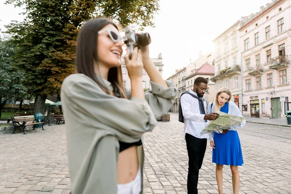 Jonge mooie toeristische vrouw verkennen van de stad, het maken van foto 's van beroemde plaatsen. Afrikaanse man en blank meisje met stadsplattegrond en het verkennen van nieuwe stadsgezichten. Reizen, vriendschap concept — Stockfoto