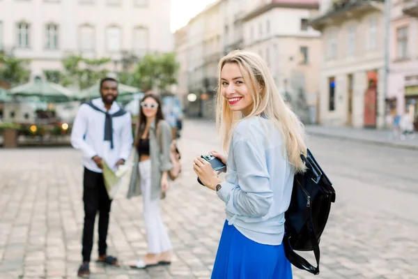 Outdoor zomer glimlachen lifestyle portret van mooie jonge blonde vrouw plezier hebben in de stad in Europa met de camera, en het maken van reisfoto 's voor stijlvolle multi-etnische paar, Afrikaanse man en wit meisje — Stockfoto