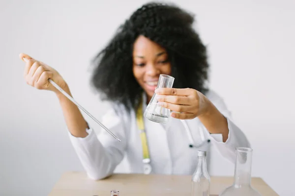 Beyaz önlüklü, steteskoplu güzel Afrikalı Amerikalı kız doktor. Laboratuvarda bir masada oturup örnek analiz etmek. Laboratuvar asistanı bir örneği analiz ediyor.. — Stok fotoğraf