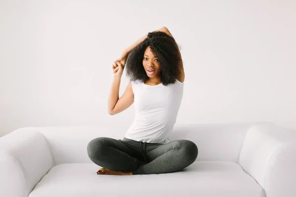 Una joven afroamericana sentada en la posición de loto sobre una cama blanca — Foto de Stock