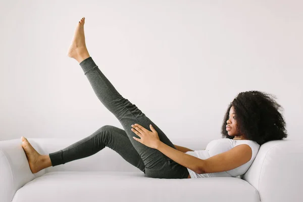 하얀 침대에 누워 운동을 하고 있는 아프리카계 미국 여성 — 스톡 사진