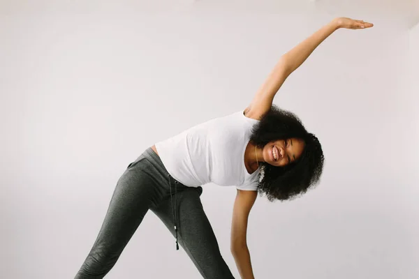 En afroamerikansk ung kvinna som står på en vit säng och motionerar. — Stockfoto