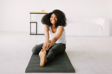 Paspasın üzerinde fiziksel egzersiz yapan Afro-Amerikalı genç bir kadın.