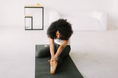 Paspasın üzerinde fiziksel egzersiz yapan Afro-Amerikalı genç bir kadın.