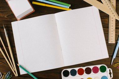 Tahta bir arkaplandaki defter, kalem, kalem ve ataçların yerleşimi..