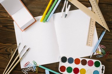 Tahta bir arkaplandaki defter, kalem, kalem ve ataçların yerleşimi..