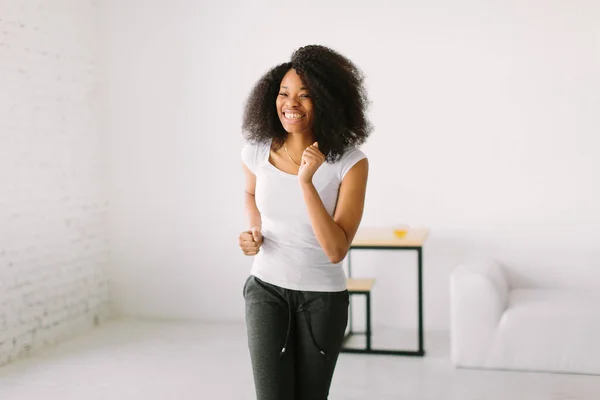 Una giovane donna afroamericana che fa esercizi fisici in piedi in un tappeto — Foto Stock