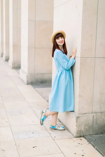 Belle jeune femme rousse en robe bleue debout près des colonnes de Paris. Belle fille touristique marche et profiter des vacances dans la vieille ville européenne — Photo