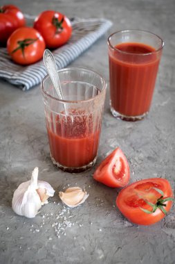 Koyu bir tahta üzerinde bir bardak taze domates suyu, domates ve sarımsak.