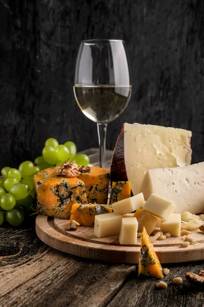 Pieces of Jugas and Shropshire Blue  cheese with grapes on a wooden plate at  background