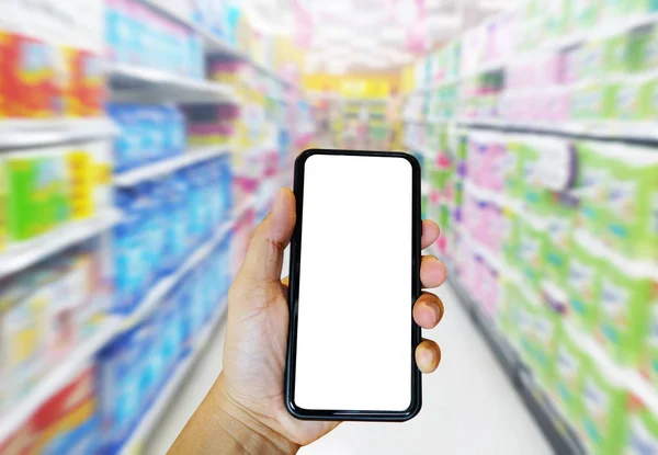 Mão segurando telefone inteligente para compras supermercado on-line com fundo de supermercado borrado. E-commerce e conceito de tecnologia . — Fotografia de Stock