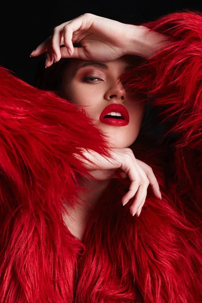 Winter Woman with red lips in Luxury Red Fur Coat. Beauty Fashion Model Girl portrait with perfect Makeup and clear skin. Beautiful glamour Luxury Winter Lady.