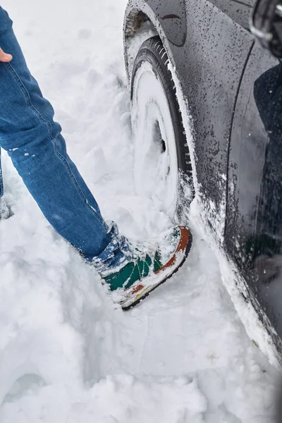 car stuck in snow. Man trying to clean the snow to free the car