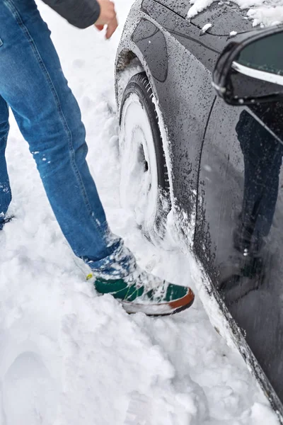 car stuck in snow. Man trying to clean the snow to free the car