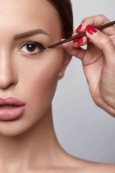 Woman doing eye make-up using black eye liner. Beautiful woman close-up. Beauty skin healthy and perfect makeup.