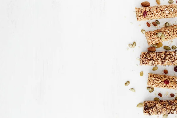 Granola bar. Healthy organic sweet dessert snack. Cereal granola bar with nuts, fruit and berries on a white wooden table. Top view.