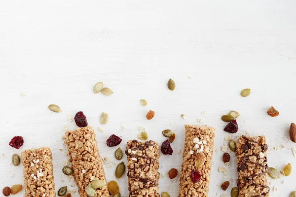 Granola bar. Healthy organic sweet dessert snack. Cereal granola bar with nuts, fruit and berries on a white wooden table. Top view.