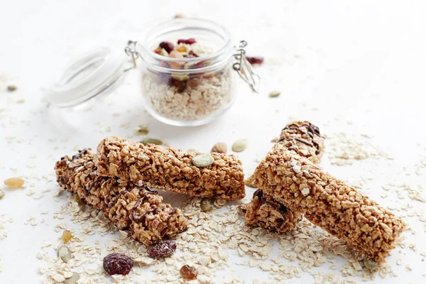 Granola bar and oatmeal. Healthy organic sweet dessert snack. Cereal granola bar with nuts, fruit and berries on a white table.