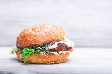Vejetaryen burger, domates, soğan keten tohumu ve susamlı taze çörek. Sebzeli vejetaryen mercimek burger. Işık arkaplanı, kopyalama alanı. Vejetaryen gıda konsepti.