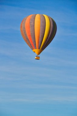 Parçalı bulutlu gökyüzü altında yükselen bir sıcak hava balonu.