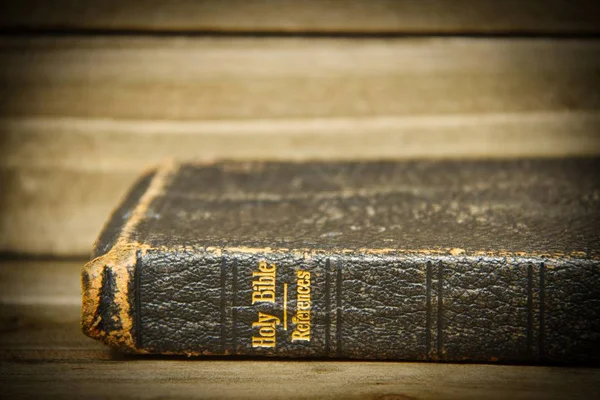 一本圣经放在它一边的木桌上 只有脊柱的焦点与轻微的插图 — 图库照片