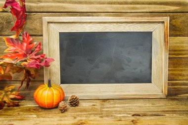 Balkabağı ve bazı diğer sonbahar dekorasyonları ile boş bir kara tahta.