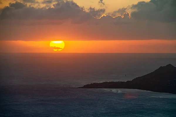 A sunset over the Hawaiian Island of Oahu as seen from a mountain top with Diamond Head in the distance.  Image captured from the summit of Koko Head Crater.