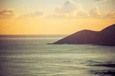 Hawaii adalarındaki uzak bir dağın ardında akşam gökyüzü Pasifik Okyanusu 'nun akşam gökyüzünün renklerini yansıtıyor..