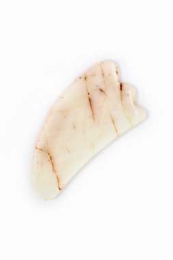Gua sha doğal taşı beyaz arka planda izole edildi. Gua sha masaj tabağı elmacık kemiklerini yontmak için ideal bir alettir..