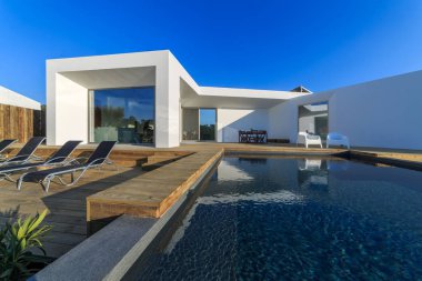 Bahçe havuzu ve ahşap güvertesi olan modern bir ev.