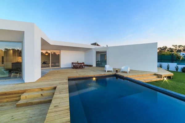 Bahçe havuzu ve ahşap güvertesi olan modern bir ev.
