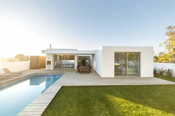 Bahçe havuzu ve ahşap güvertesi olan modern bir ev.