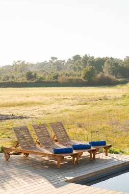 Modern villa havuzunda ahşap şezlonglar.