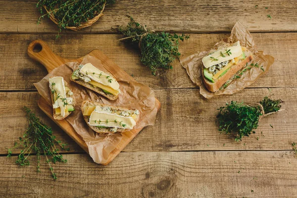 Healthy sandwiches with avocado, cheese and herbs. On wooden background. — Stock Photo, Image