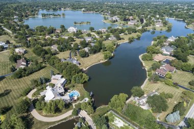 Ağaçlarla kaplı, yazın gölleri olan lüks bir banliyö mahallesinin havadan görünüşü..