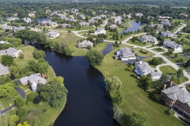 Yazın çeşitli göletleri olan, ağaçlarla kaplı, lüks bir banliyö mahallesinin havadan görünüşü.