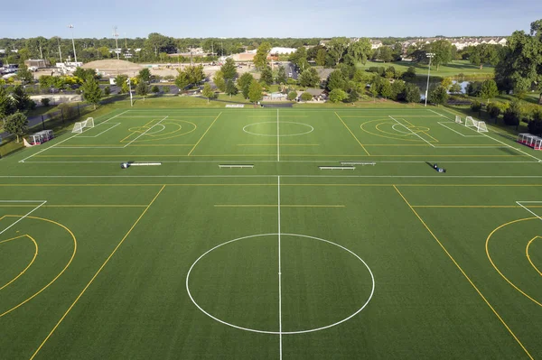 Aerial view of a multi-use playfield with soccer/lacrosse fields with lights in a suburban setting.