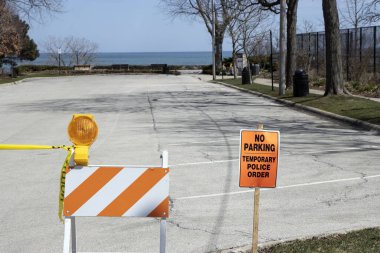 Yerel bir belediye, 2020 Coronavirus salgını sırasında sosyal mesafeyi ve ev izolasyonunu desteklemek için Glencoe, Illinois 'de Michigan Gölü kıyısındaki tanınmış bir banliyö plajının yakınındaki bir otoparkı kapatır..