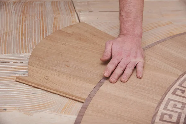 The carpenter installs one of the decorative elements of the parquet. — Stock Photo, Image